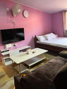 a living room with two beds and a table and a tv at Twendzetu kilifi in Kilifi +3 photos