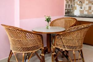a table with three chairs and a table with a vase of flowers at Varkala Days Home Stay in Varkala