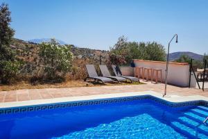 a swimming pool with two lounge chairs next to it at Gusta la Vista in Ríogordo