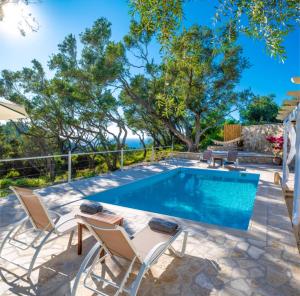 a swimming pool with two chairs and a table with at Olive Cottage in Petrátika