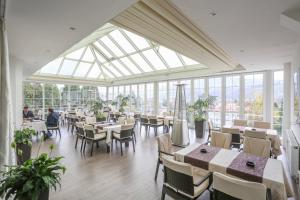 a dining room with tables and chairs and windows at Hotel Park in Vogošća