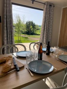 a wooden table with plates and bottles and glasses on it at Camping Du Perche Bellemois in Bellême