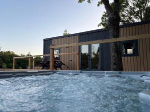 a swimming pool with a tree in front of a building at Camping Du Perche Bellemois in Bellême