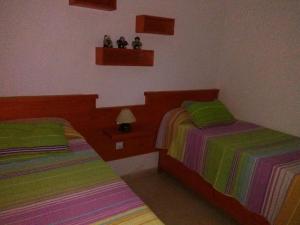 カレタ・デ・ファマラにあるFamara Paraísoの緑色とカラフルなシーツが備わるベッドルームのベッド2台