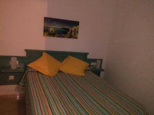 1 dormitorio con 1 cama con almohadas amarillas en Famara Paraíso en Famara