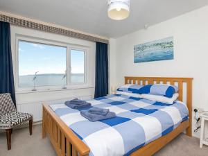 a bedroom with a bed and a large window at Gosteg in Moelfre
