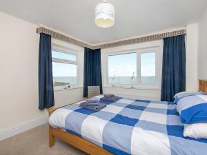 a bedroom with a blue and white bed and two windows at Gosteg in Moelfre