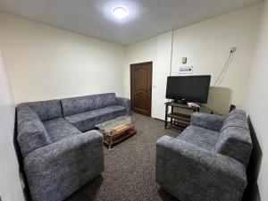 a living room with two couches and a flat screen tv at Sultan Palace Apartments in Wadi Musa
