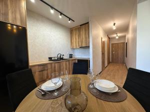 a wooden table with plates and wine glasses on it at Apartament w centrum 5A in Iława