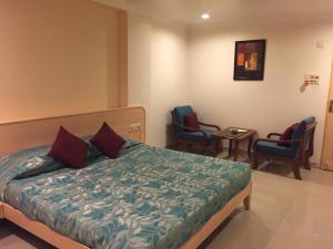 博帕尔Hotel Sarthak的一间带一张床和两把椅子的酒店房间