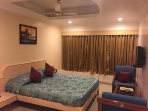 博帕尔Hotel Sarthak的一间卧室，里面有一张床、一把椅子和一扇窗户