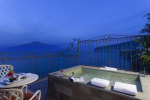 a bath tub on a balcony with a view of the ocean at Grand Hotel Ambasciatori in Sorrento