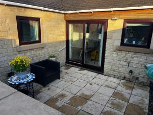 eine Terrasse mit Glastür und einem Tisch mit Blumen in der Unterkunft Witz End in Corsham