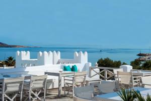 a beach area with chairs, tables and umbrellas at Kanale's Rooms & Suites in Naousa