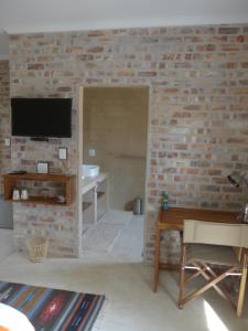 a living room with a brick wall and a tv at Hadassa Guest House in Otjiwarongo +9 photos