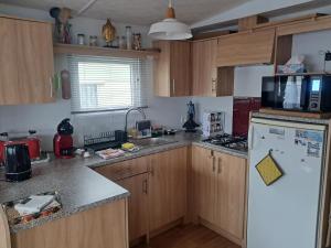 eine Küche mit Holzschränken und einem weißen Kühlschrank in der Unterkunft Lolasurmer in Bredene