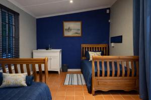 a bedroom with two beds and a blue wall at 12a Infinity Guesthouse in Pietermaritzburg