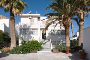 a white building with palm trees in front of it at Kamari Blue Boutique Hotel in Kamari