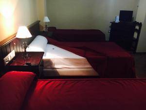 a hotel room with two beds and two lamps at Hostal Pechi in Huévar