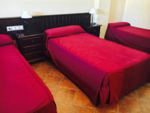 1 dormitorio con 2 camas con sábanas rojas en Hostal Pechi, en Huévar