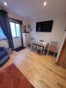 ein Wohnzimmer mit einem Tisch und einem Fernseher an der Wand in der Unterkunft Orkneyinga in Kirkwall
