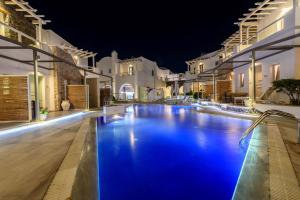 a swimming pool at night with white buildings at La Mer Deluxe Hotel & Spa in Kamari