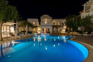 a large blue pool in front of a house at night at La Mer Deluxe Hotel & Spa in Kamari