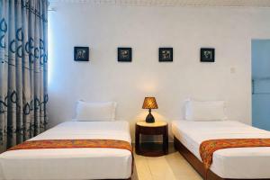 two beds in a room with a lamp on a table at The Residence Dambulla in Dambulla