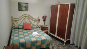 Schlafzimmer mit einem Bett mit einem roten Kissen und einem Schrank in der Unterkunft Pensión Lacasta in Saragossa