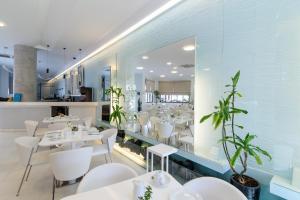 un restaurante con mesas blancas y sillas blancas en La Mer Deluxe Hotel & Spa, en Kamari