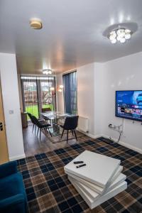 a living room with a table and chairs and a tv at The Way House in Manchester