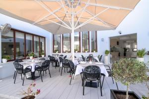 a restaurant with white tables and chairs and large windows at La Mer Deluxe Hotel & Spa in Kamari