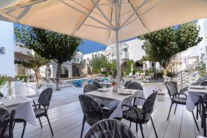 Un patio con mesas y sillas y una sombrilla. en La Mer Deluxe Hotel & Spa, en Kamari