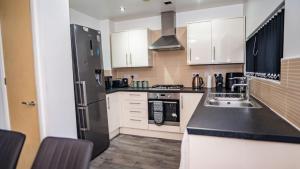 a kitchen with white cabinets and a black refrigerator at The Way House in Manchester