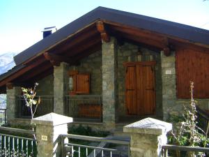 a stone house with wooden doors and a fence at La Maison Nouva 1977 in Aosta
