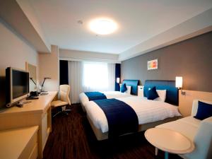 横浜市にあるダイワロイネットホテル新横浜の大型ベッドとテレビが備わるホテルルームです。