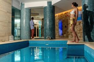 a woman standing next to a swimming pool at La Mer Deluxe Hotel & Spa in Kamari