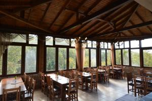 a dining room with tables and chairs and windows at Guesthouse Rodamos in Taxiarchis