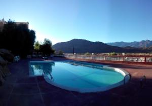 a large swimming pool with mountains in the background at Hotel Les Amandiers in Tafraoute