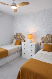 a bedroom with two beds and a night stand with a lamp at NUEVO-LUZ DE CONIL piscina y parking in Conil de la Frontera