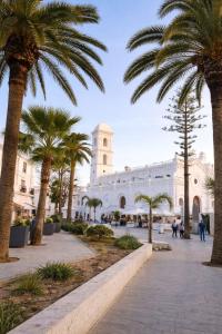 a white building with palm trees in a courtyard at NUEVO-LUZ DE CONIL piscina y parking in Conil de la Frontera