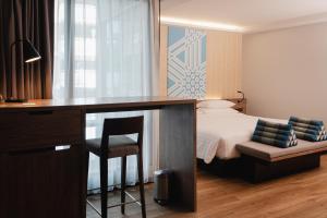a hotel room with a bed and a desk with a desk at RakYim Siam - Sukhumvit 15 in Bangkok