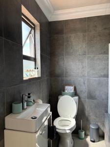 a bathroom with a toilet and a sink and a window at Sebeshong Guest House - Moletjie in Ga-Komape +45 photos