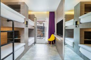 a room with bunk beds with a tv and a yellow chair at GaasBaasCompany, Thamel, Kathmandu in Kathmandu