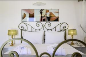 a white bed with two tables and two lamps at La Mer Deluxe Hotel & Spa in Kamari