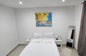 a white bedroom with a bed and a painting on the wall at Bilene Harmony Home in Vila Praia Do Bilene