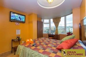 - une chambre avec un lit et une télévision murale dans l'établissement Hotel Gran Quitumbe, à Quito
