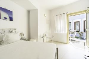 a white bedroom with a white bed and a window at La Mer Deluxe Hotel & Spa in Kamari