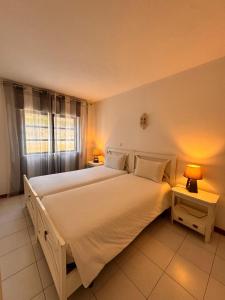 a bedroom with a large white bed with two lamps at Cardoso Beirao in Carvoeiro +23 photos