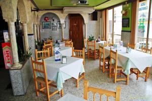 a restaurant with white tables and wooden chairs at Hostal Mary Tere in Salobreña